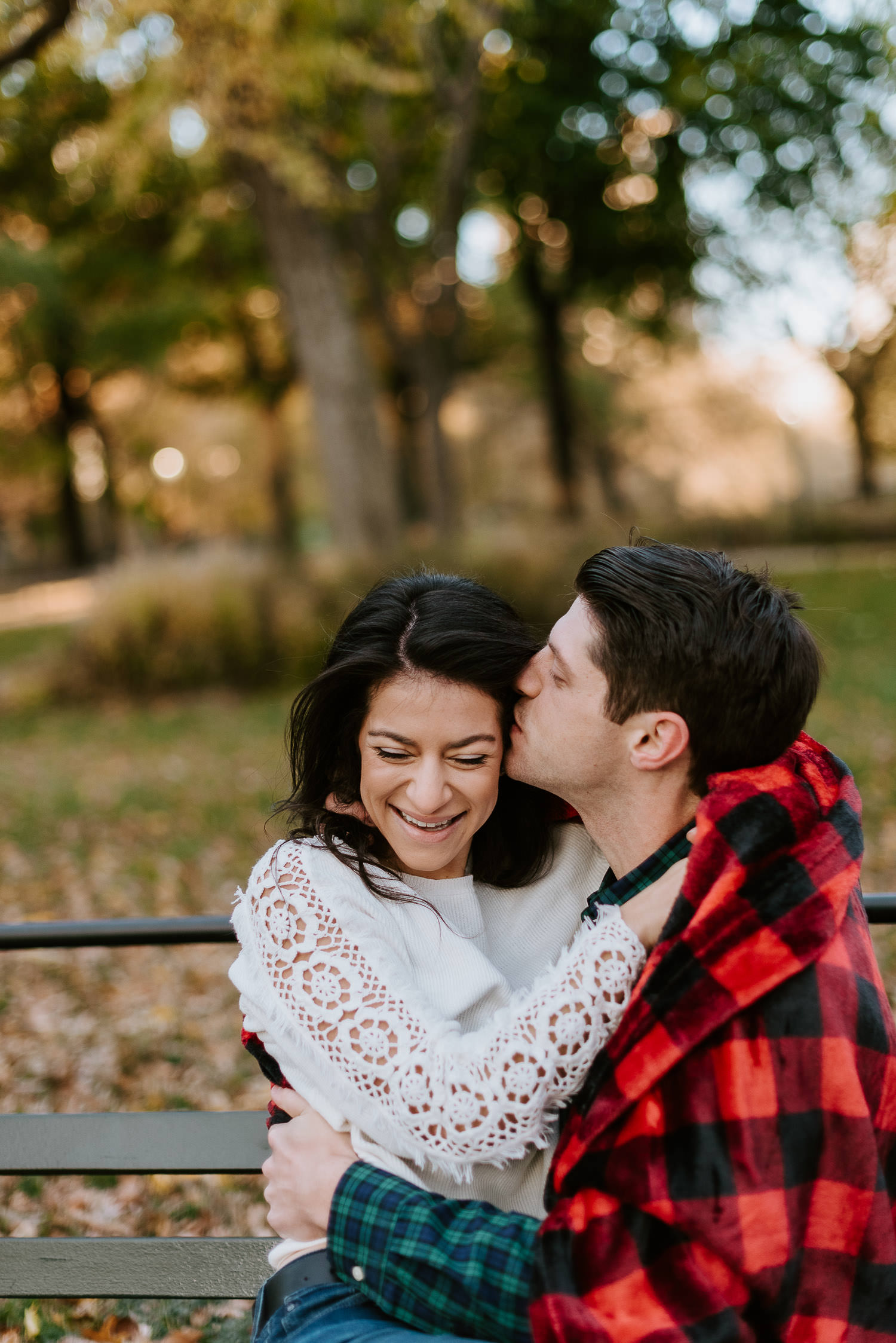 man kissing his fiancee's cheek in central park during their engagement photos
