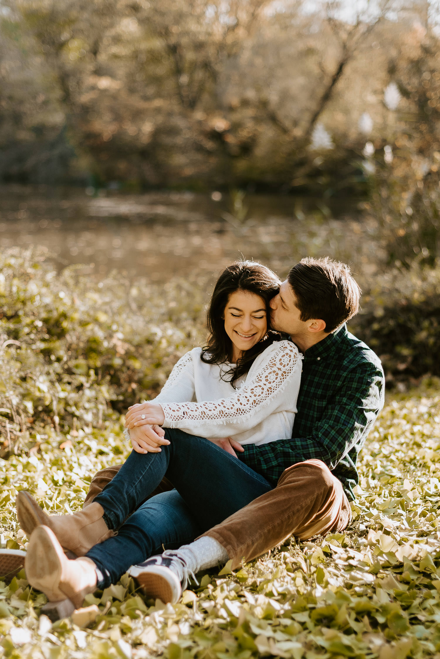 engaged couple kissing and hugging in the grass in central park in november during their photoshoot